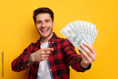 Foto Smiling Young Caucasian Male Displaying Cash Money At Studio With Yellow Background, Excited About Financial Success And Wealth