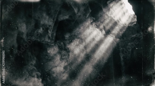 Abstract dark background with dramatic light rays piercing through thick smoke