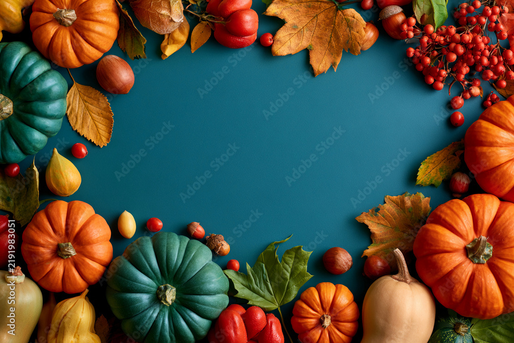Fototapeta premium Arrangement of pumpkins, peppers, leaves, and nuts on a blue surface during autumn