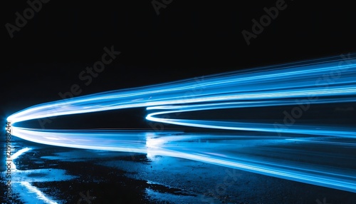 Abstract long-exposure photography of luminous electric-blue light ribbons sweeping in elegant S-curves across a rain-soaked asphalt surface at night, vivid reflections shimmering in the wet pavement