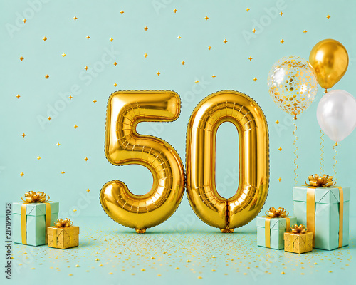 Gold 50 balloon number for 50th birthday anniversary celebration with gift boxes and confetti