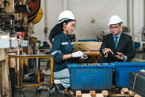 Fotografie Industrial worker and businessman inspect metal components in factory workshop,