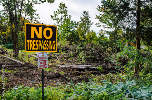 Fotografie No Trespassing sign in the foreground of a woodlot clear cut project