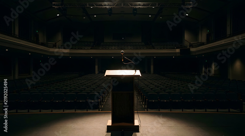 Empty Wooden Podium with Microphone on Stage in Dark Auditorium for Public Speaking, Keynote Presentations, and Leadership Conference Events