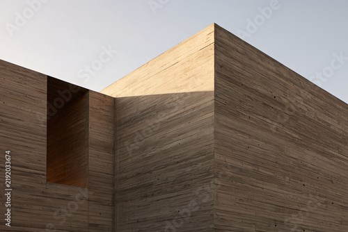 Corner of a board-formed concrete building with a deep window recess against a pale sky
