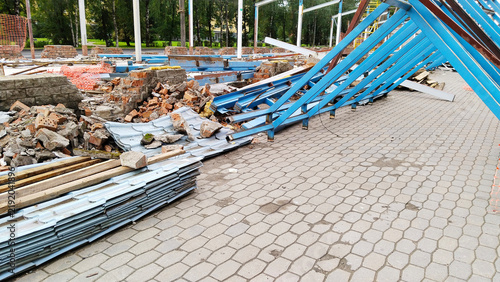 Dismantling steel frame structure on building demolition site. metal beams and corrugated roof tiles sheets on ground. Urban architecture wreckage scrap waste recycling background. Safety Risk