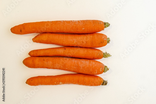 Canvastavla Row of fresh whole carrots laid horizontally with trimmed green tops visible on
