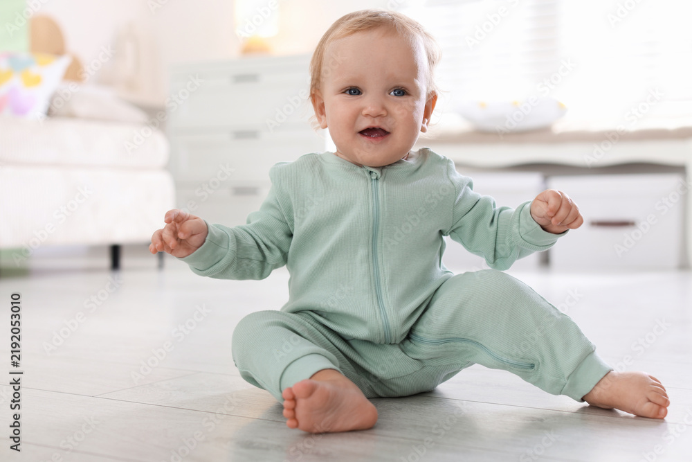 Fototapeta premium Cute little baby in onesie on floor at home