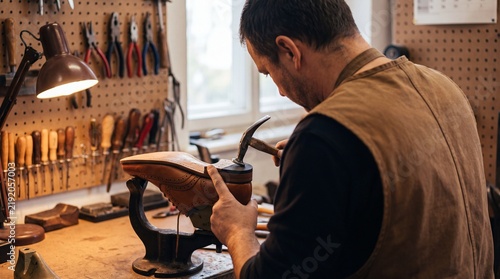 Cobbler repairing a leather shoe in workshop with tools