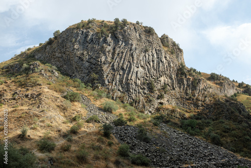 Fotografía Layered basalt rock formation in Armenia, featuring greenery and rocky ground, w