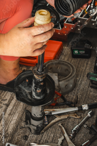 Close-up of a mechanic assembling a car shock absorber, replacing suspension strut bump stop and dust boot in a garage, professional automotive repair and maintenance concept.