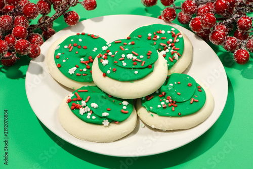 Frosted sugar cookies on a white plate with berries in the background