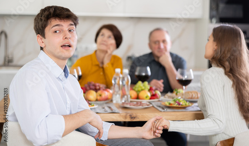 Photography Shocked concerned young man sitting at table during family conversation with eld