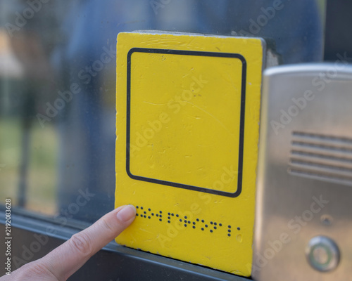 A blind woman reads the braille sign next to a call button.