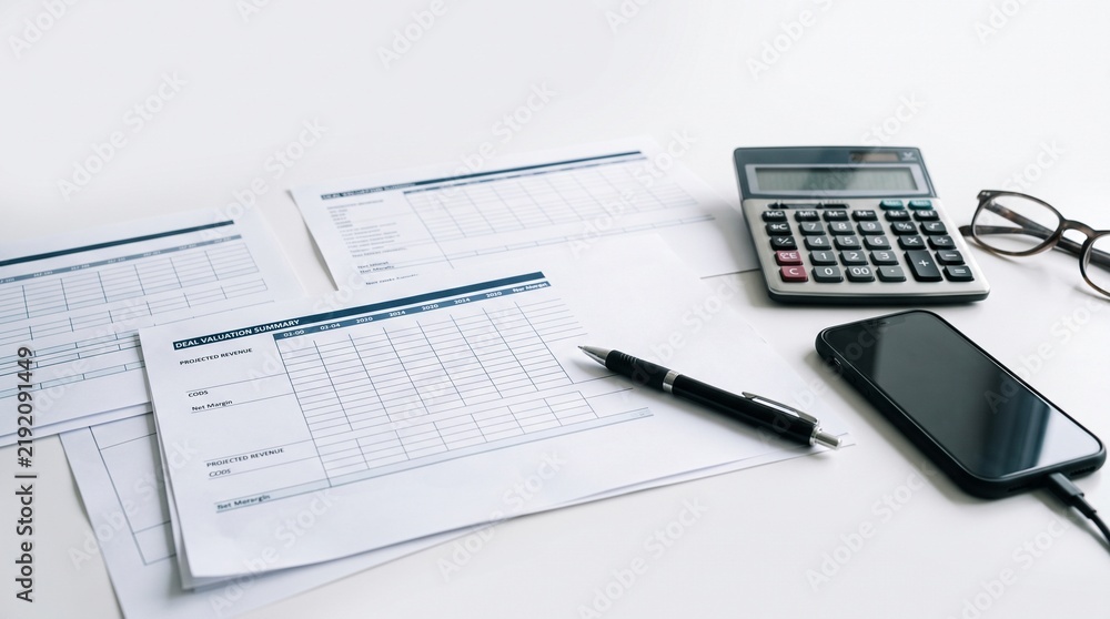 Obraz premium Office desk with spreadsheet printouts calculator smartphone and glasses