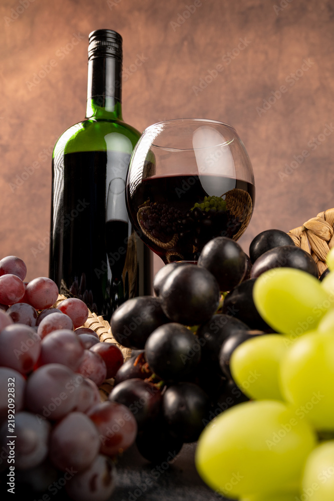Obraz premium Arrangement of grapes and a bottle of red wine; beautiful grapes, a bottle of red wine, and accessories on a stone surface; abstract background, selective focus.