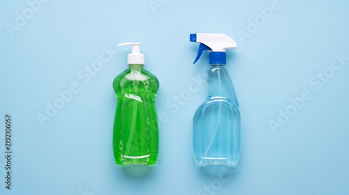 Two bottles of cleaning supplies, dish soap and spray, on a blue background