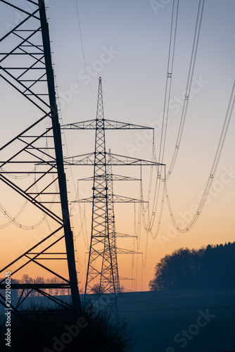 Electricity pylons and transmission lines at dusk