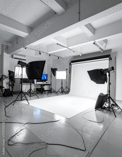 Professional photo studio with white backdrop and lighting equipment, no people.