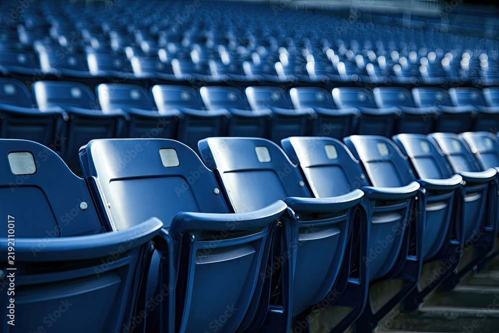 Fototapeta premium Rows of empty, blue stadium seats stretch into the distance, bathed in light