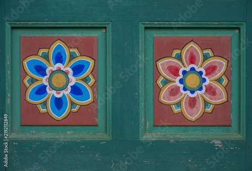 Obraz na płótnie Vibrant blue and pink painted lotus flower motifs adorn the green wooden door panels of a traditional Korean temple