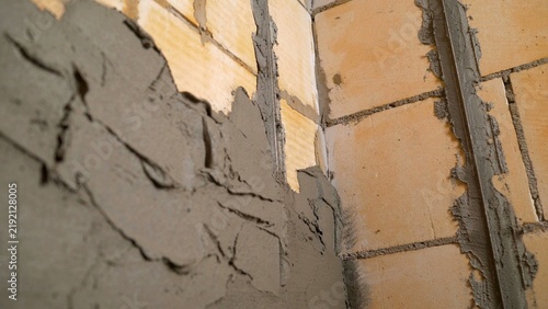 Close up of plasterer applying fresh concrete plaster on a wall during renovation