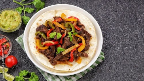 Beef fajitas made with tender strips of seasoned beef, colorful bell peppers, and onions, served hot with soft flour tortillas. Tex-Mex food