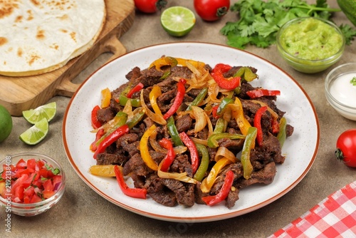 Beef fajitas made with tender strips of seasoned beef, colorful bell peppers, and onions, served hot with soft flour tortillas. Tex-Mex food