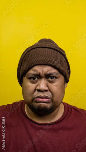Quadro su tela An adult Indonesian male displays a sad, pouting expression while looking directly at the camera