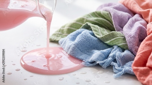 Pink Liquid Detergent Poured onto Colorful Fabrics, Symbolizing Laundry Care, Fabric Softener, and Household Cleaning