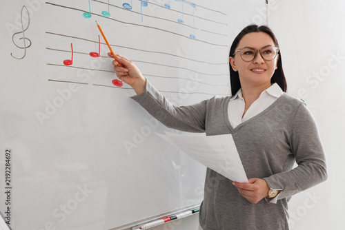 Female music teacher showing notes on whiteboard in classroom