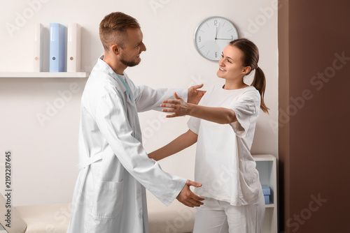 Male doctor with patient hugging in clinic