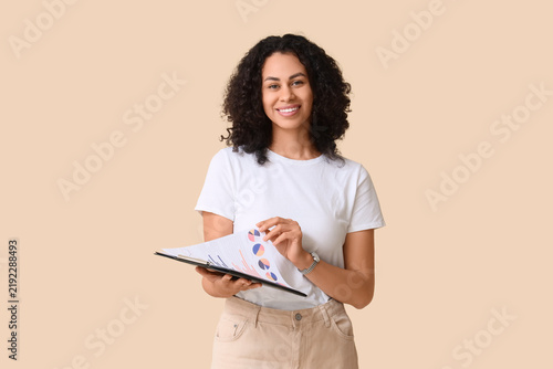 Young African-American woman with diagrams on beige background