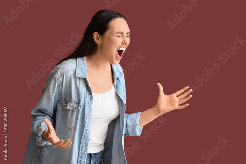 Screaming young woman on burgundy background