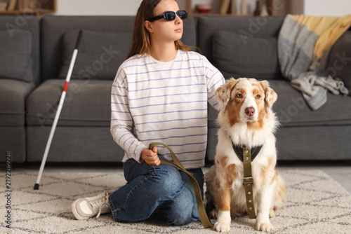 Blind young woman with guide dog sitting on carpet at home