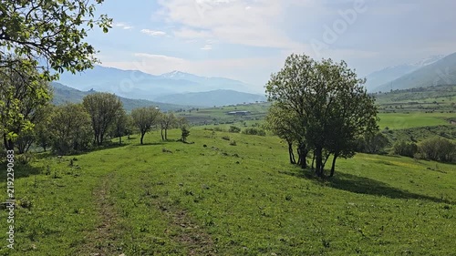 Green trees dot a rolling meadow overlooking a wide valley and distant snow-streaked mountains, beneath a spring sky streaked with soft clouds.
📍 Marivan, Kurdistan, Iran 