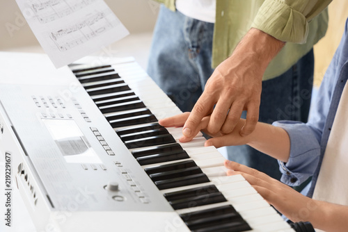 Private music teacher giving synthesizer lessons to boy at home, closeup