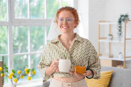 Young redhead woman with turmeric drink at home