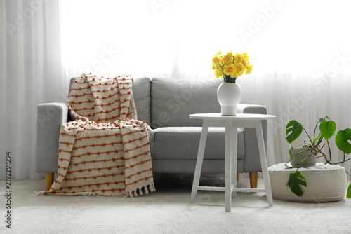 Interior of living room with sofa and narcissus in vase