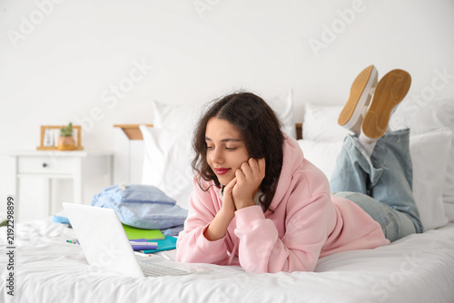 Female Indian student studying with laptop in bedroom