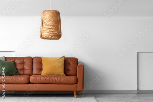 Brown leather sofa near white wall in room