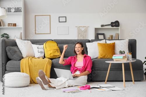 Happy teenage girl with laptop excited about being accepted to college at home