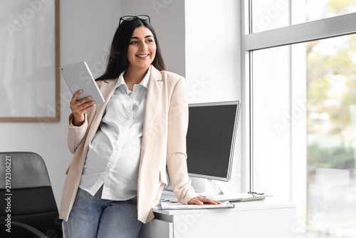 Pregnant businesswoman with tablet computer in office