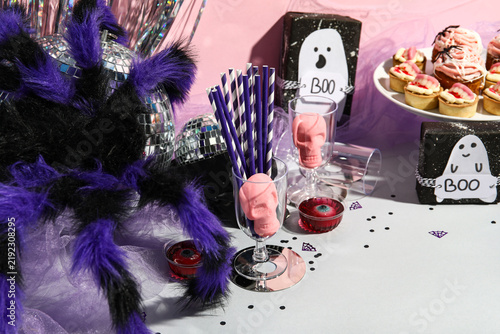 Halloween gifts with party decor on table against pink background