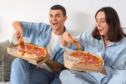 Young couple with tasty pepperoni pizza at home