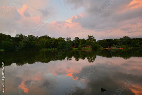 Sunset-iinfused color in the clouds is reflected onto the surface of a lake. The colors provided by the day's fading light were deepened and enhancds by the lake's still, darkened water.