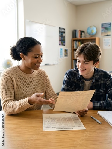 Female teacher explaining test results on paper document to teenage male student