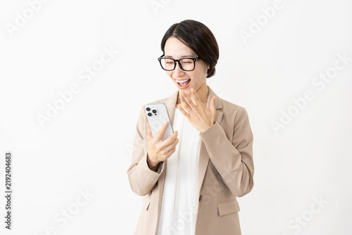 фотографія スマトフォンを使う眼鏡をかけたスーツ姿の女性