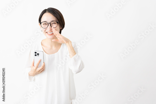 スマートフォンを使うメガネをかけたカットソー姿の女性　ライフスタイルイメージ