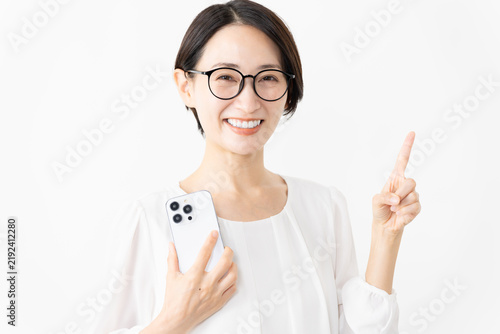 スマートフォンを使うメガネをかけたカットソー姿の女性　ライフスタイルイメージ